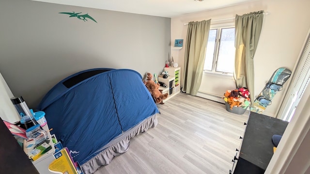 bedroom featuring baseboard heating and wood finished floors