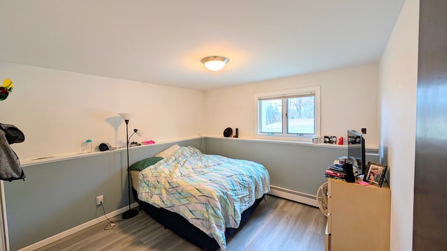 bedroom featuring a baseboard radiator, baseboards, and wood finished floors