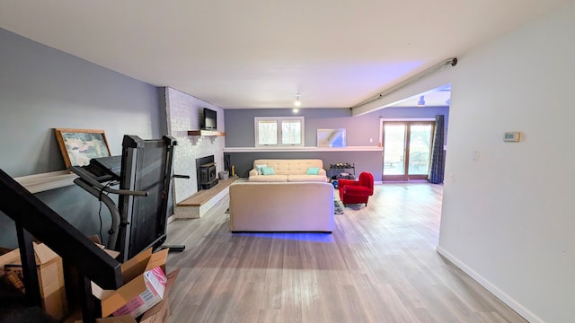 living room with a fireplace, baseboards, and wood finished floors