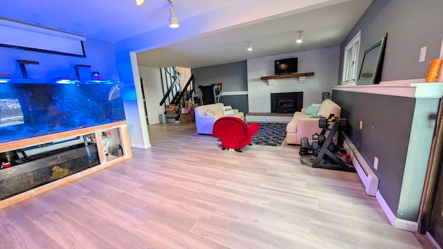 interior space featuring a fireplace, wood finished floors, baseboards, stairway, and baseboard heating