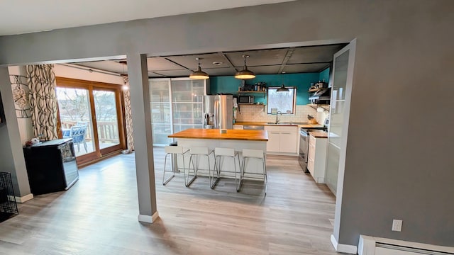 kitchen with open shelves, stainless steel appliances, a baseboard radiator, a sink, and wood counters