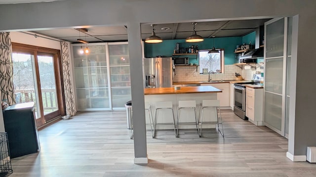 kitchen featuring a drop ceiling, stainless steel appliances, a sink, wood counters, and open shelves