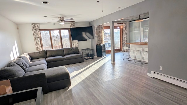 living area with visible vents, a baseboard radiator, wood finished floors, and a wealth of natural light