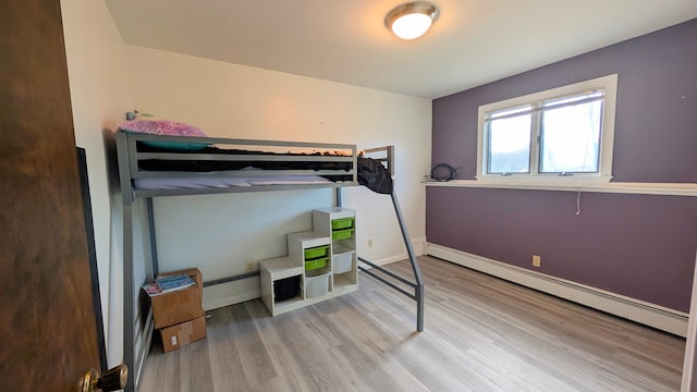 bedroom with baseboard heating, wood finished floors, and baseboards