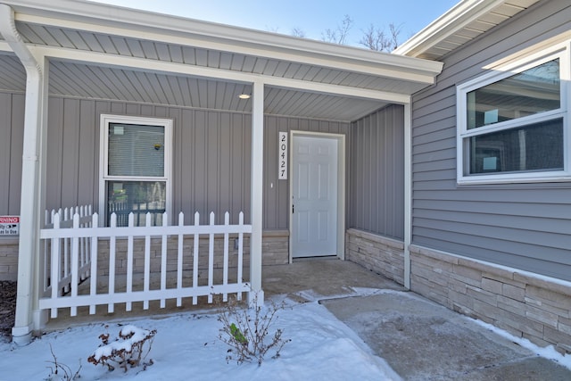 snow covered property entrance with covered porch