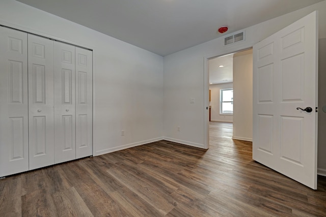 unfurnished bedroom featuring dark wood-type flooring and a closet