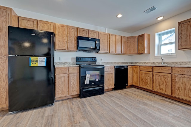 kitchen featuring sink, light hardwood / wood-style flooring, and black appliances