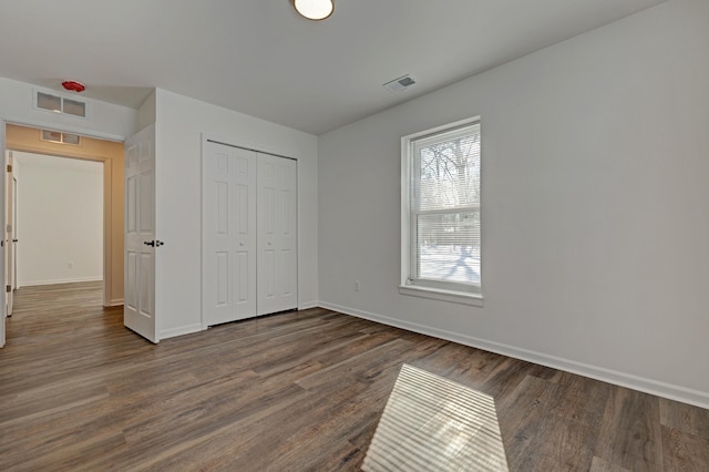 unfurnished bedroom featuring dark hardwood / wood-style flooring and a closet