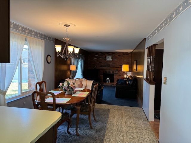 dining space with a fireplace, a chandelier, and brick wall