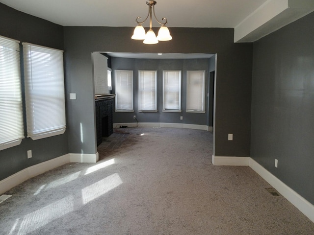 unfurnished living room with carpet, a healthy amount of sunlight, and a notable chandelier