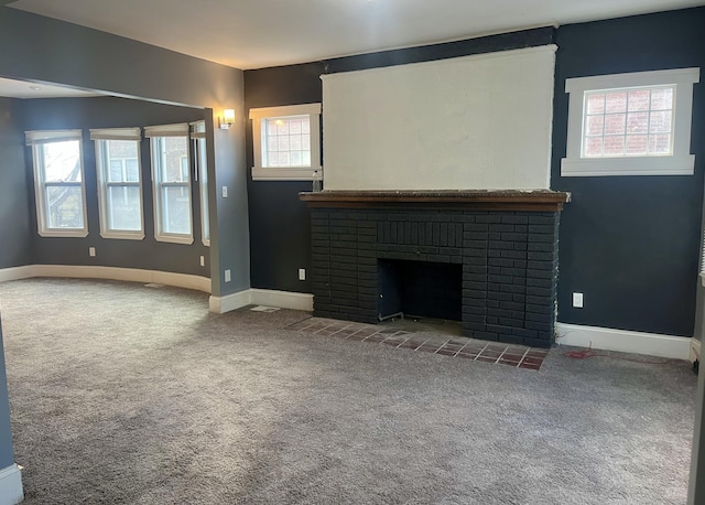 unfurnished living room featuring a fireplace, a wealth of natural light, and carpet flooring