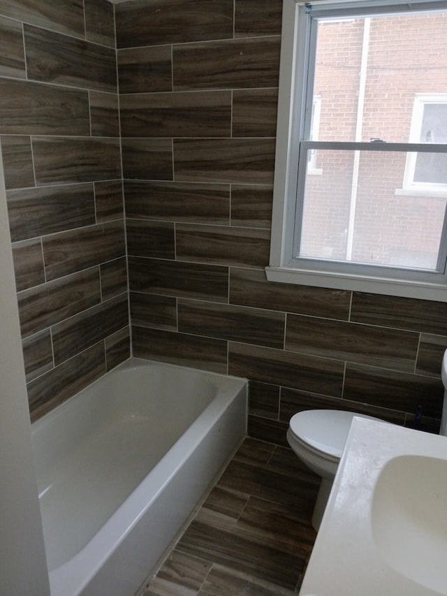 full bathroom with tile walls, sink, a wealth of natural light, and toilet