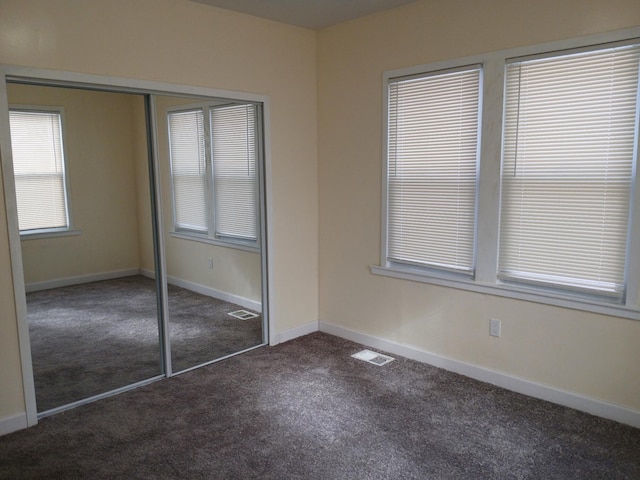 unfurnished bedroom featuring a closet and dark colored carpet