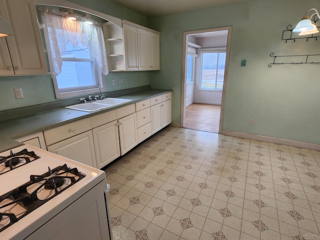 kitchen with sink, gas range gas stove, and white cabinets