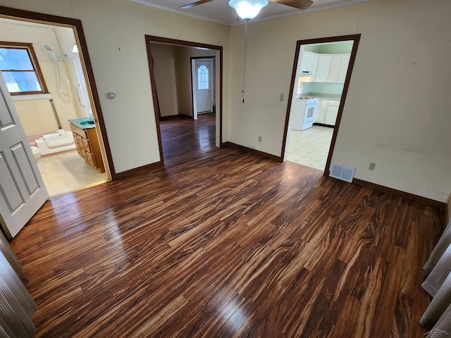 spare room with a wealth of natural light, dark wood-type flooring, and ornamental molding