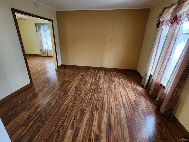 spare room featuring crown molding and dark hardwood / wood-style flooring