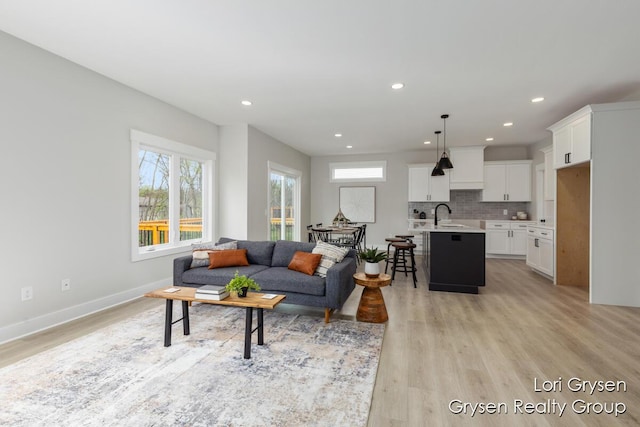living room with recessed lighting, baseboards, and light wood-style flooring