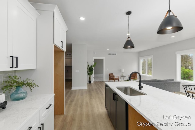 kitchen with visible vents, a sink, open floor plan, and light stone countertops