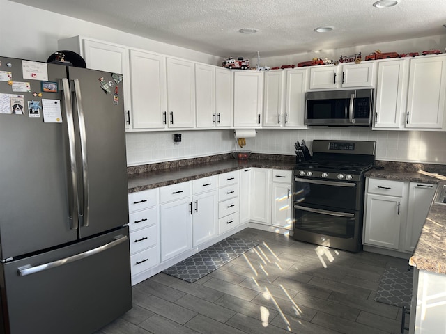 kitchen featuring backsplash, a textured ceiling, white cabinets, and appliances with stainless steel finishes