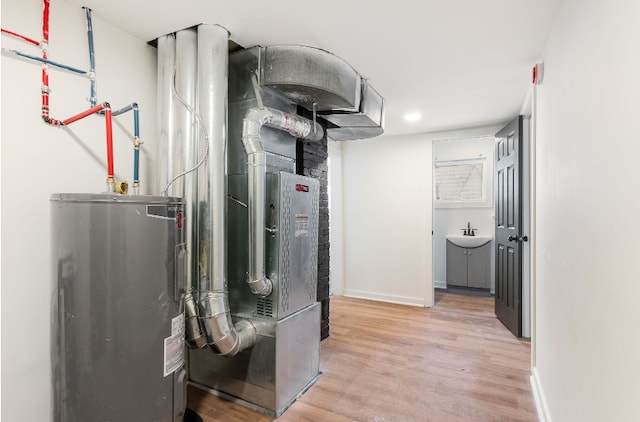 utilities featuring sink, electric water heater, and heating unit