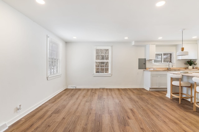 kitchen with light hardwood / wood-style flooring, pendant lighting, white cabinets, and electric panel