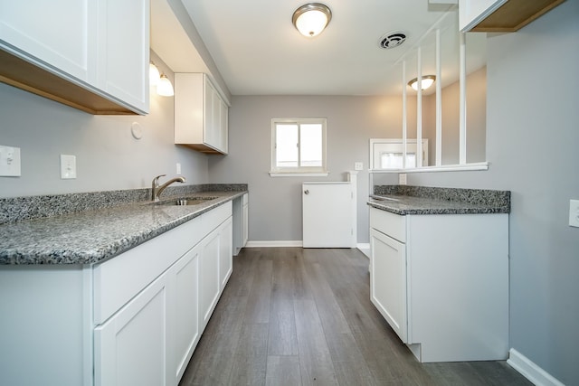 kitchen featuring sink, dark wood-type flooring, dark stone counters, and white cabinets