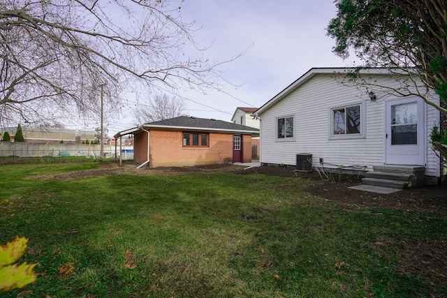 back of property with a carport, a yard, and central air condition unit