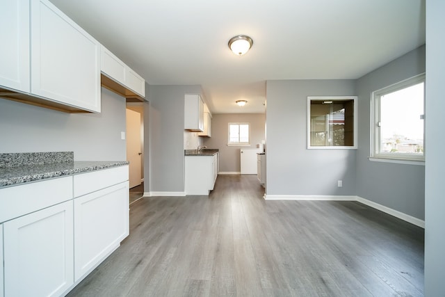 kitchen with dark stone countertops, white cabinets, and light hardwood / wood-style flooring