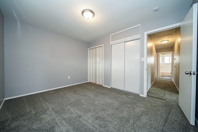 unfurnished bedroom featuring multiple closets and dark carpet