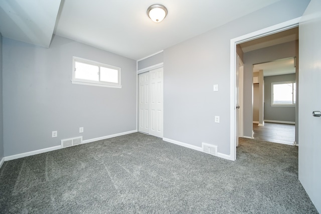 unfurnished bedroom featuring a closet and dark colored carpet