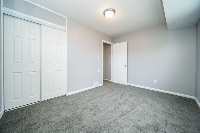 unfurnished bedroom with dark carpet and a closet