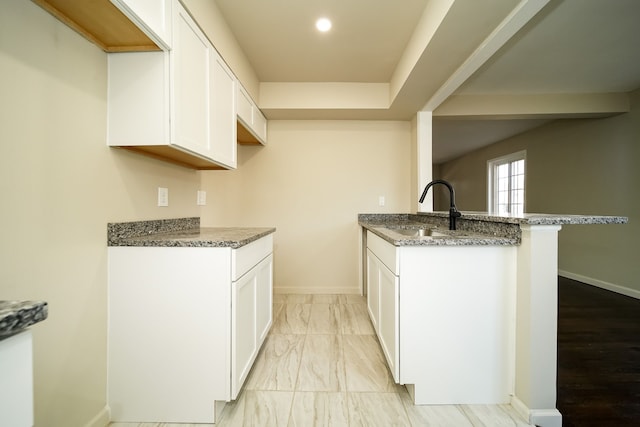 kitchen featuring sink, dark stone counters, and white cabinets