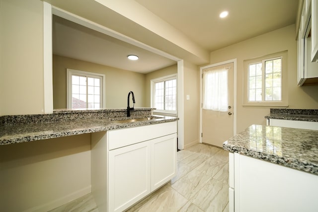 kitchen with sink, light stone countertops, and white cabinets