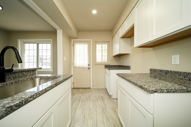 kitchen featuring white cabinetry, stone countertops, and sink