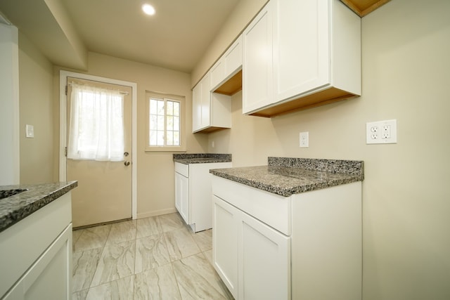 kitchen featuring white cabinetry and dark stone counters