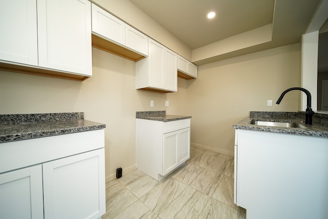 kitchen featuring white cabinetry, sink, and dark stone counters