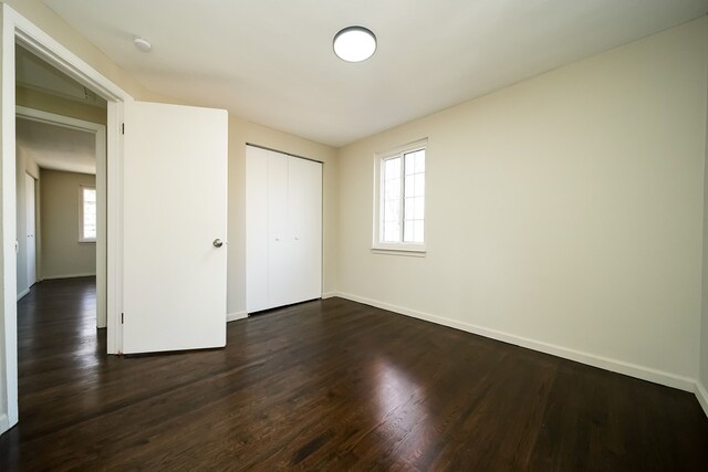 unfurnished bedroom featuring dark wood-type flooring and a closet