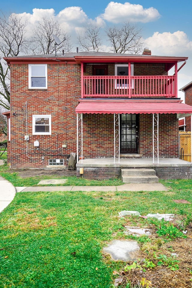 view of front of home with covered porch, a front yard, and brick siding