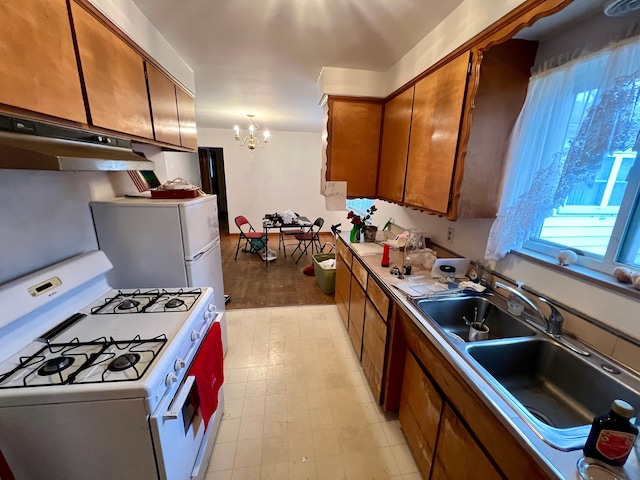 kitchen with a chandelier, sink, fridge, white gas stove, and pendant lighting