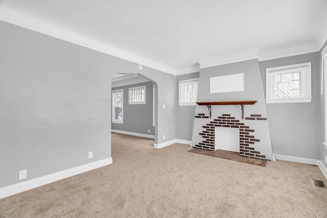 unfurnished living room featuring ornamental molding, a wealth of natural light, and light colored carpet