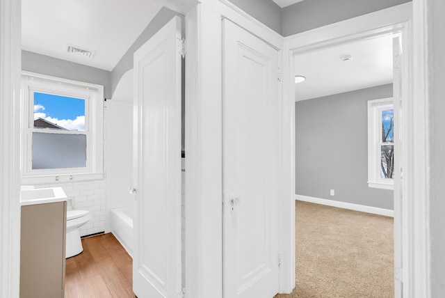 corridor featuring light carpet and tile walls