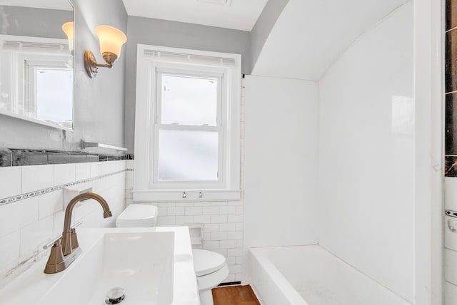 bathroom with sink, hardwood / wood-style flooring, tile walls, a bath, and toilet