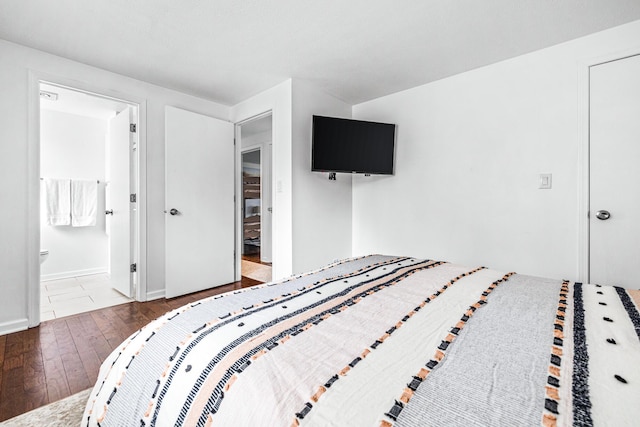 bedroom with dark wood-type flooring and connected bathroom