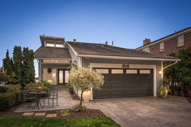 view of front facade featuring a garage, driveway, and a shingled roof