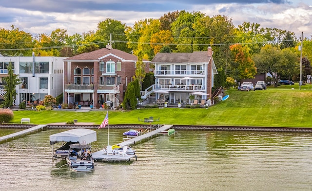 exterior space featuring a balcony, a yard, and a water view