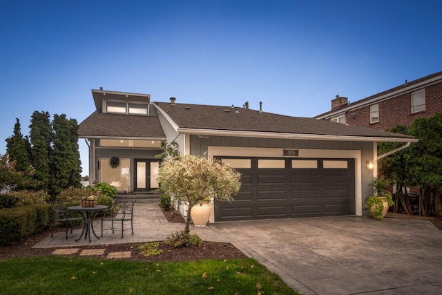 view of front facade featuring an attached garage, concrete driveway, and a shingled roof