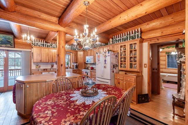 dining room with an inviting chandelier, beam ceiling, rustic walls, and hardwood / wood-style floors