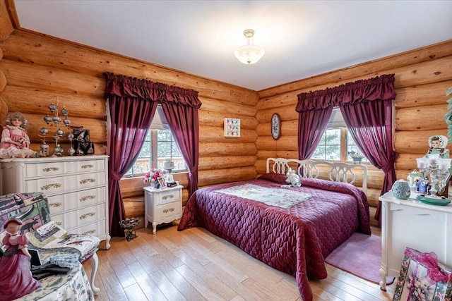 bedroom with multiple windows, light hardwood / wood-style floors, and rustic walls