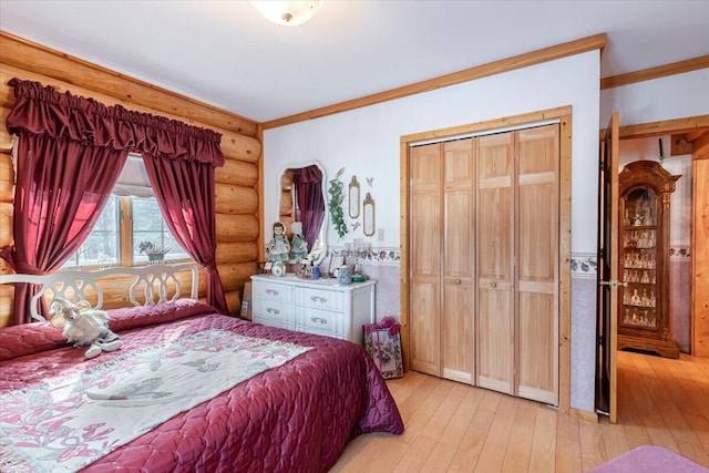 bedroom with a closet, log walls, crown molding, and light hardwood / wood-style flooring