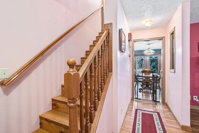 staircase featuring hardwood / wood-style floors and a textured ceiling